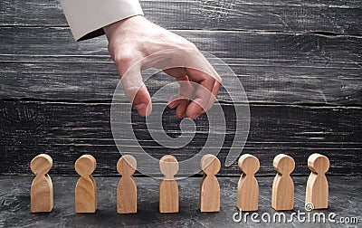 The businessman`s hand hangs over the figures of people and prepares them to grab. The dismissal of workers, the destruction Stock Photo
