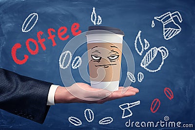 A businessman`s hand holding a coffee cup with a drawn unhappy grumpy face on it. Stock Photo