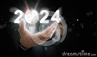 Businessman`s hand holding the year 2024 with light blub, dart, and target. Starting the new year, business, project, path, goal, Stock Photo