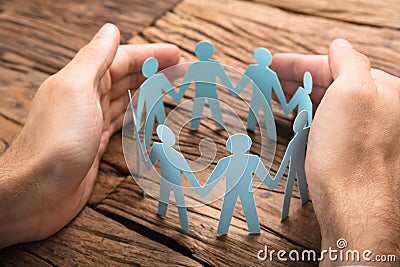 Businessman`s Hands Covering Paper Team On Table Stock Photo