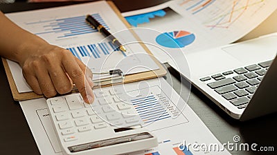 Businessman`s hands pressing a calculator, calculating, analyzing, graphing, charting, accounting worker working on a laptop. A ba Stock Photo