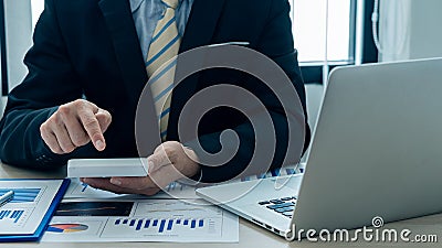 Businessman`s hands pressing a calculator, calculating, analyzing, graphing, charting, accounting worker working on a laptop. A ba Stock Photo