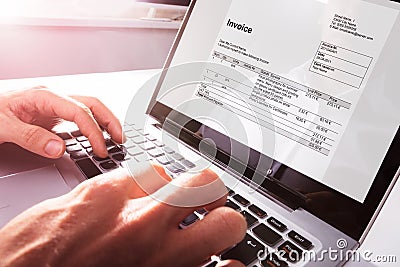 Businessman`s Hands Working On Invoice On Laptop Stock Photo