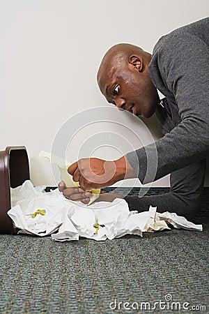 Businessman searching through rubbish bin Stock Photo