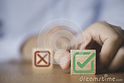 Businessman select green correct sign mark between Red Cross mark which print screen on wooden cube block for approve and reject Stock Photo