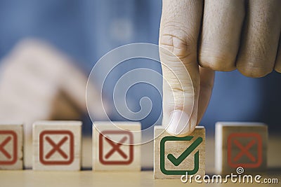 Businessman select green correct sign mark between Red Cross mark which print screen on wooden cube block for approve and reject Stock Photo