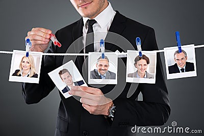 Businessman selecting candidate from clothesline Stock Photo