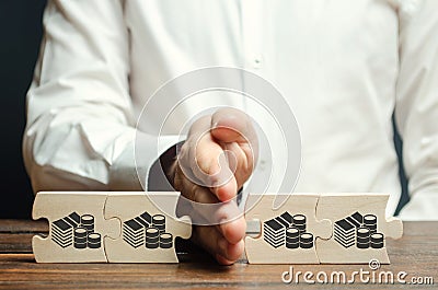 Businessman separates the wooden puzzle with a picture of money. The concept of financial management and distribution of funds. Stock Photo