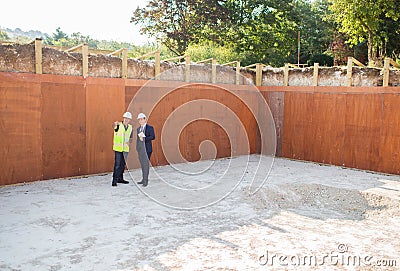 Businessman Shaking Hands With Builder On Construction Site Stock Photo