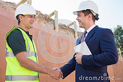Businessman Shaking Hands With Builder On Construction Site Stock Photo
