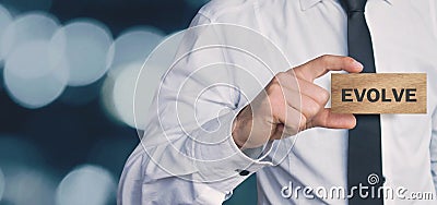 Businessman showing Evolve word in wooden block. Business concept Stock Photo