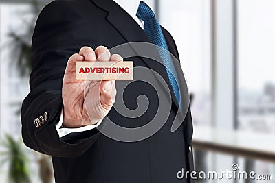 Businessman shows a wooden block with the word advertising. Business advertisement Stock Photo