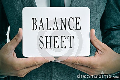 Businessman with a signboard with the text balance sheet Stock Photo