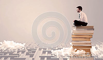 Businessman sitting on books in labirynth Stock Photo