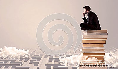 Businessman sitting on books in labirynth Stock Photo