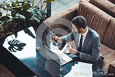 Businessman sitting in a business center restaurant browsing social media top view Stock Photo