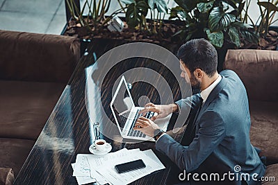 Businessman sitting in a business center restaurant typing on laptop top view Stock Photo