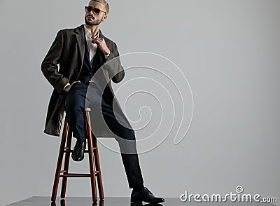 Businessman sitting one leg resting and looking sideways intrigued Stock Photo