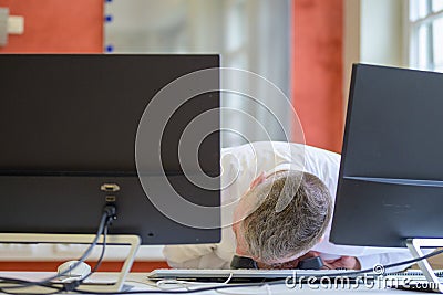 Businessman sitting slumped over his desk in office Stock Photo