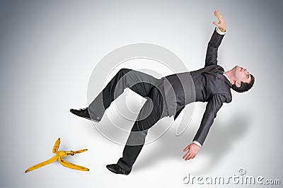 Businessman slipping and falling from a banana peel Stock Photo