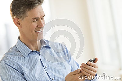 Businessman Smiling While Messaging Through Mobile Phone Stock Photo