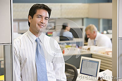 Businessman standing in cubicle smiling Stock Photo