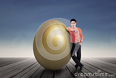 Businessman standing by a huge golden egg Stock Photo