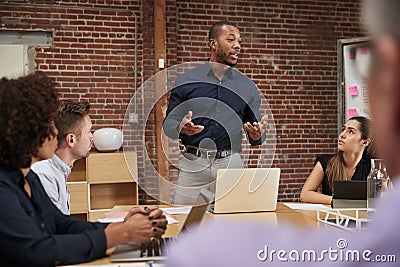 Businessman Standing And Leading Office Meeting Around Table Stock Photo