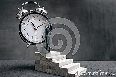 Businessman stands on stairs and tries to change clock hand Stock Photo