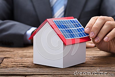 Businessman Sticking Solar Panel On Model Home Stock Photo