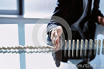 businessman stopping dominoes with his hand. close-up. Stock Photo