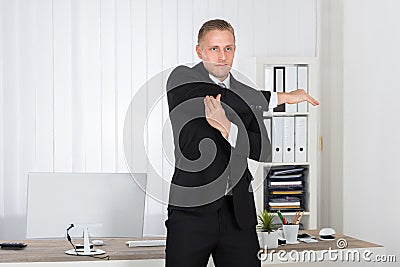 Businessman Stretching In Office Stock Photo