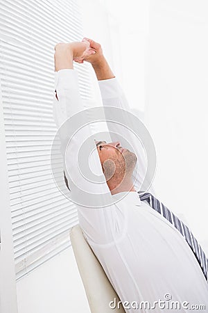 Businessman stretching in swivel chair Stock Photo