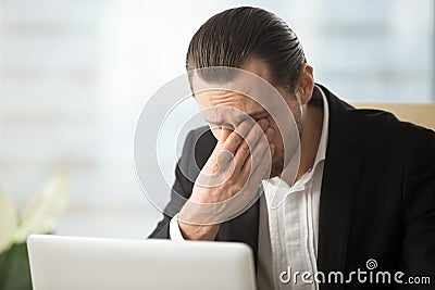 Businessman suffering from eyes fatigue at work Stock Photo