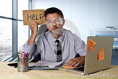 Businessman suffering stress working at computer desk holding sign asking for help looking tired exhausted Stock Photo