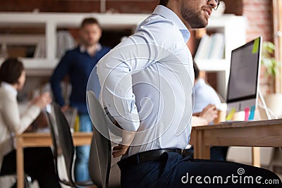 Businessman suffers from lower back pain sitting in shared office Stock Photo