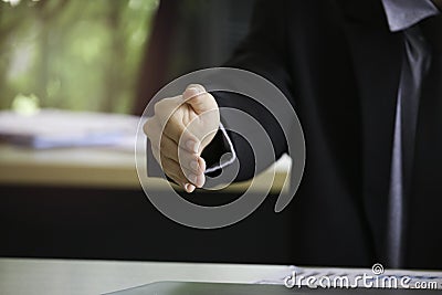 Businessman in suit giving hand for handshake with copyspace, man with open hand ready to seal a deal at workplace Stock Photo