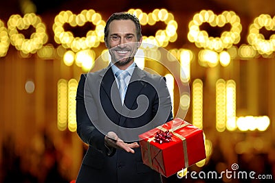 Businessman in suit is presenting big red gift box. Stock Photo