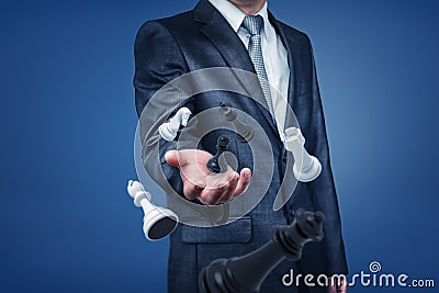 A businessman in suit standing with only upper-body visible, holding his hand out as if to reach chesspieces floating in Stock Photo
