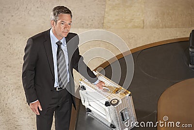 Businessman With Suitcase At Luggage Carousel In Airport Stock Photo