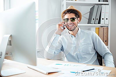 Businessman in sunglasses talking on cell phone in office Stock Photo