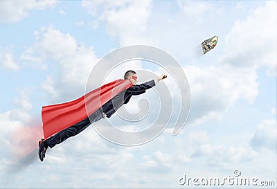 A businessman in a superhero cape flying in the sky trying to catch a 100 USD banknote. Stock Photo