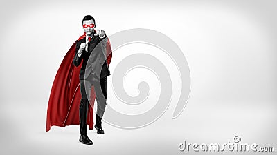 A businessman in a superhero red cape and a mask throwing punches in the air on white background in high contrast shot. Stock Photo