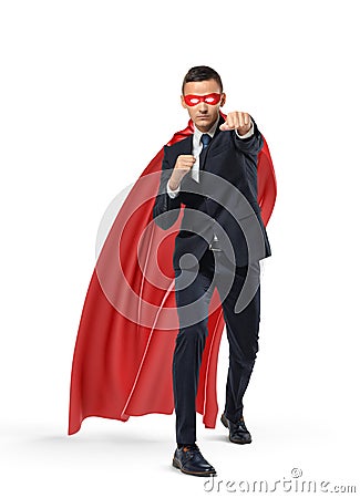 A businessman in a superman red cape and a mask standing in punch position on white background. Stock Photo