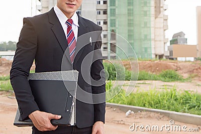 Businessman surveying land for industrial project. Stock Photo