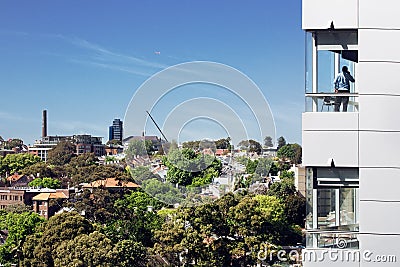 Businessman talking on phone by the window of a building with the view of a Sydney, Australia Editorial Stock Photo