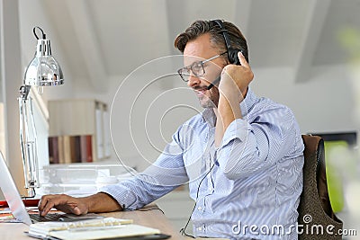 Businessman teleworking with headset on laptop Stock Photo