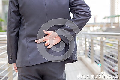 Businessman telling lies, hold crossed finger his back with modern building background Stock Photo