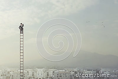 Businessman at the top of a long ladder observes the city with his binoculars Stock Photo