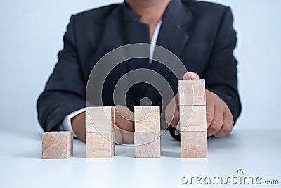 Businessman touches the woodblocks placed on the table Stock Photo
